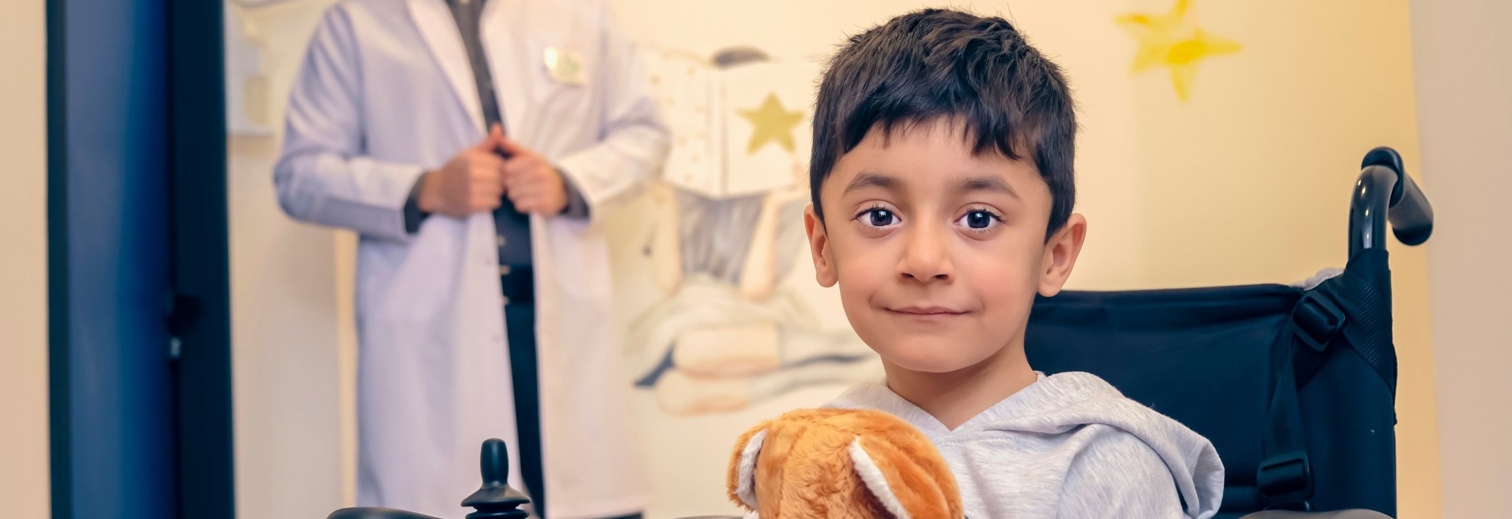 Young boy in a wheelchair holding stuffed animal